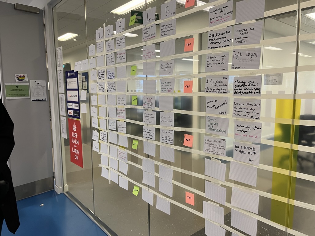 A glass wall office partition covered in post-it notes, and index cards in a grid.
